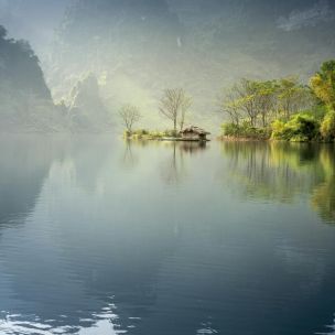 Scenic view of a foggy lake surrounded by lush mountains in Tuyên Quang, Vietnam.