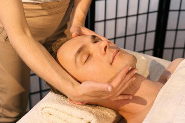 A serene massage setting with a man receiving facial relaxation therapy for ultimate stress relief.